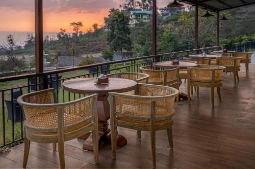 a restaurant with tables and chairs on a balcony at The Atman Dharamshala by Leisure Hotels in Dharamshala