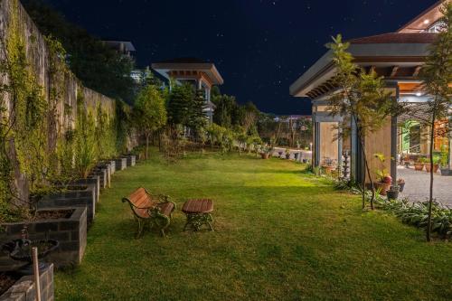 a yard with chairs and a table in the grass at The Atman Dharamshala by Leisure Hotels in Dharamshala
