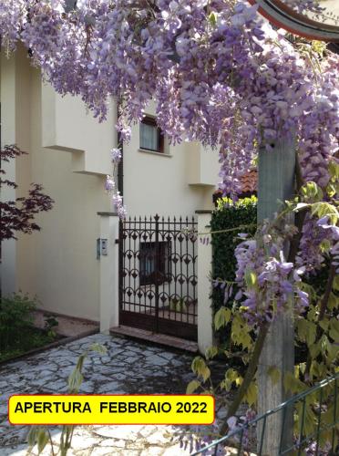 a fence with purple flowers on it next to a building at B&B Piccole Dolomiti in Belluno