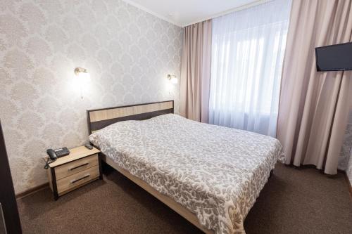 a bedroom with a bed and a dresser and a window at Hotel Mir in Kyiv