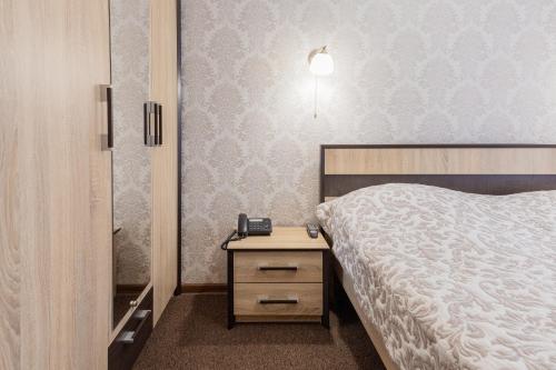 a bedroom with a bed and a phone on a night stand at Hotel Mir in Kyiv