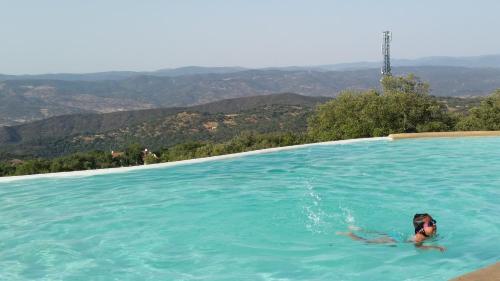 a woman swimming in a swimming pool with mountains in the background at Finca El Chaparral in Cortelazor