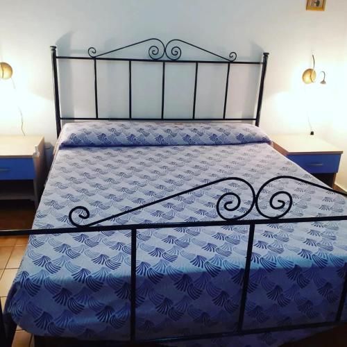 a bed with a blue comforter on it with two tables at La Casa di Anna in Lampedusa