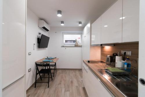 una cocina con armarios blancos y una mesa pequeña. en Room at Vacation Station en Piran