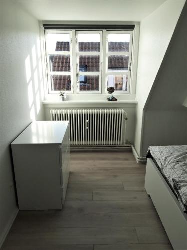 um quarto com uma cama, uma janela e um radiador em Nabo til domkirken em Viborg