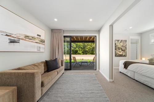 a bedroom with a couch and a bed and a window at Lake Luxe - Taupo in Taupo