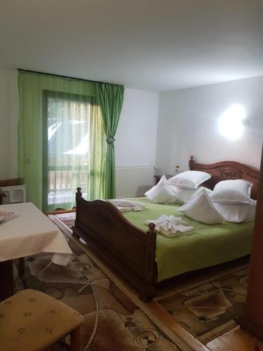a bedroom with a bed with green sheets and a window at Grandemi Belvedere Bucovina in Frasin