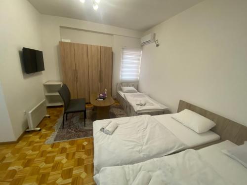 a room with two beds and a table and a chair at Apartmani Hadžić in Živinice