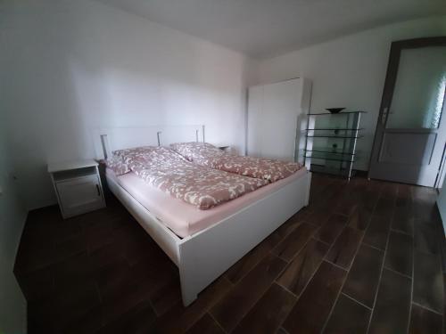 a bedroom with a bed and a wooden floor at Forrás-hegyi Apartman in Felsőörs