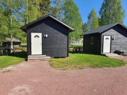 a small black building with two white doors and grass at Mora Life, Åmåsängsgården in Mora