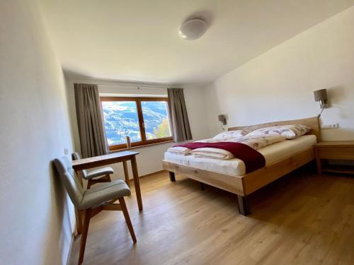 a bedroom with a bed and a desk and a window at Ferienwohnung Trattner in Bramberg am Wildkogel