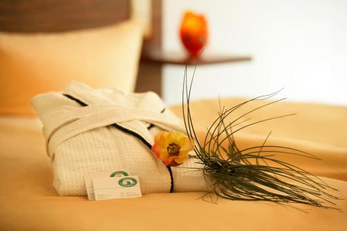 a white towel with a flower on a couch at Hotelpark der Westerwald Treff in Oberlahr