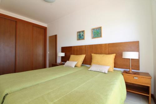 a bedroom with a large green bed with two pillows at Falesia Beach Apartment in Albufeira