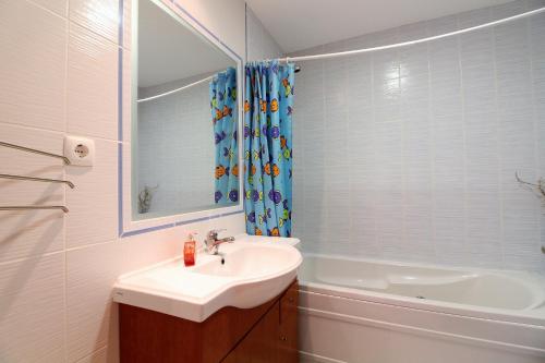 a bathroom with a sink and a tub and a mirror at Falesia Beach Apartment in Albufeira