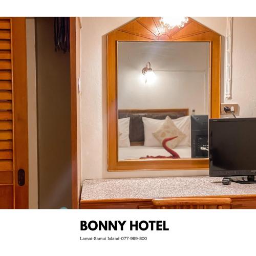 a mirror reflecting a bed in a hotel room at Bonny Hotel 4 Floors No Elevator in Lamai