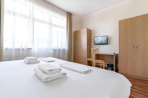 a bedroom with a white bed with towels on it at Rosa Ski Inn Hotel Rosa Khutor in Estosadok