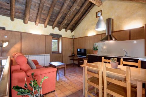 a kitchen and living room with a red couch and a table at Casas Rurales Molinias in Fosado