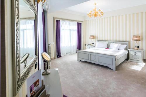 a bedroom with a white bed and a mirror at Phoenicia Grand Hotel in Bucharest