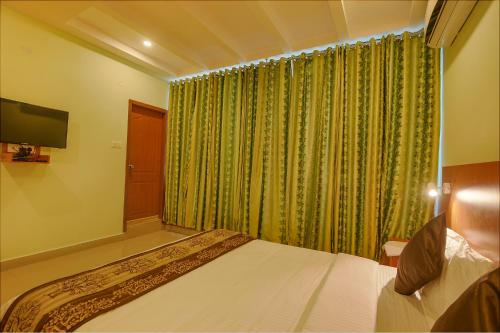 a bedroom with a bed and a green curtain at FabHotel The BTM Palace - BTM Layout in Bengaluru