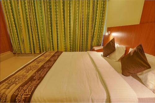 a bedroom with a large bed with white sheets and pillows at FabHotel The BTM Palace - BTM Layout in Bengaluru