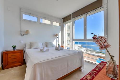 a bedroom with a large white bed and large windows at Villas Guzman - Apartamento Tramontana in Calpe