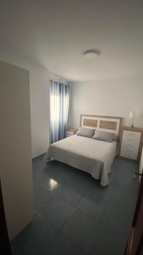 1 dormitorio con cama blanca y ventana en Apartamento Islas Malvinas 39 en Vecindario