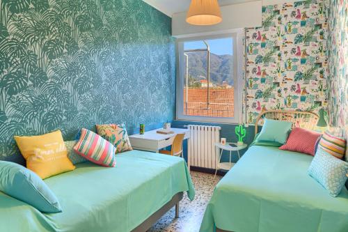 Cette chambre comprend 2 lits dans une chambre dotée de murs bleus et d'une fenêtre. dans l'établissement ALIDA House Top Floor, à Levanto
