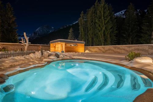 a swimming pool in a backyard at night at Croce Bianca Leisure & Spa Hotel in Canazei