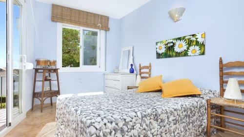 カレリャ・デ・パラフルジェリにあるRoc 1D - Calella de Palafrugellの青い壁のベッドルーム1室、黄色い枕付きのベッド1台が備わります。