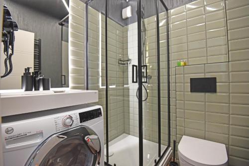 a bathroom with a shower and a washing machine at Čiki Puki Purslai in Palanga