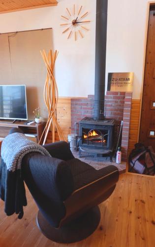 a living room with a chair and a fireplace at Ocean View House in Atami
