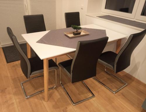 a table with black chairs and a white table with a plant on it at Ferienwohnungen Im Dorfe in Soltau