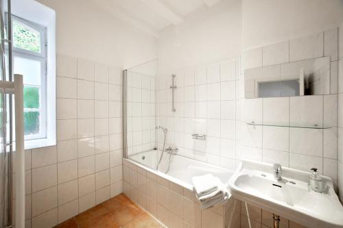 a white bathroom with a tub and a sink at Quellenhof - Wohnen im Denkmal - Wohnung "AHR" in Blankenheim