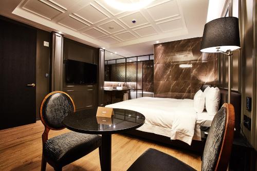 a hotel room with a bed and a table and chairs at Hotel Wanted in Incheon