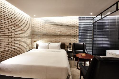 a bedroom with a white bed and a brick wall at Hotel Wanted in Incheon