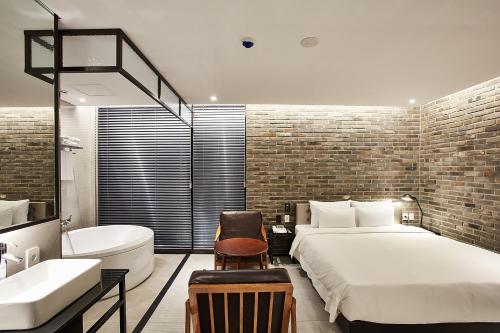 a bedroom with a bed and a tub and a sink at Hotel Wanted in Incheon