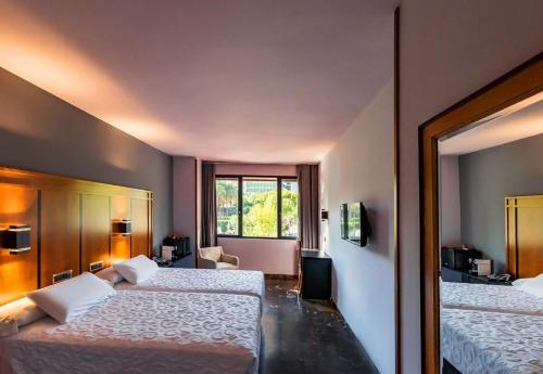 a hotel room with two beds and a window at Hotel Condestable Iranzo in Jaén