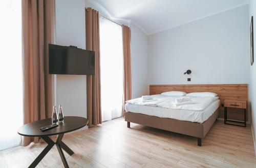 a bedroom with a bed and a table and a tv at Pokoje Venezia in Cieszyn