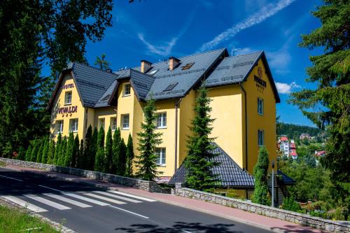 a yellow house with a black roof on the side of a road at Hotel Vivaldi in Karpacz