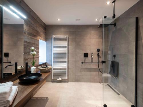 baño con ducha de cristal con lavabo negro en La Maison du Notaire, en Houffalize