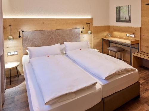 a bedroom with a large bed with white sheets at Appartementhaus Holmernhof I in Bad Füssing