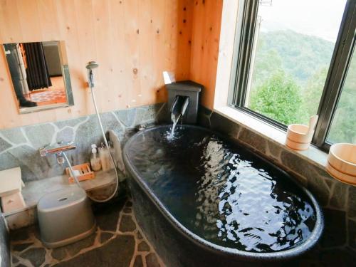 a bath tub in a bathroom with a window at Ocean View House in Atami