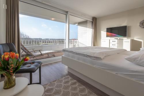 a bedroom with a large bed and a balcony at Lichtblick im Haus Cäcilia in Wenningstedt