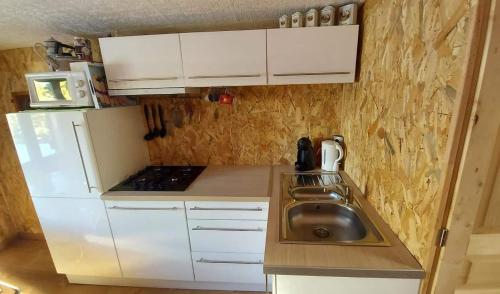 una pequeña cocina con armarios blancos y fregadero en Petit chalet Valfréjus pied des pistes, en Modane