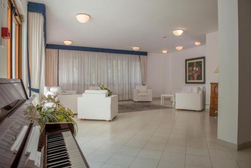 a waiting room with a piano and white furniture at Pizzomunno Vieste Palace Hotel in Vieste
