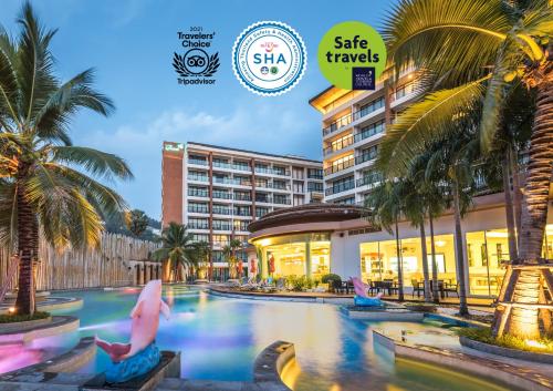 a resort swimming pool with palm trees and a hotel at The Beach Heights Resort SHA Plus in Kata Beach