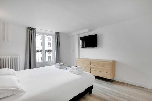 ein weißes Schlafzimmer mit einem Bett und einem TV in der Unterkunft CMG-Charmant appartement-Opéra-Galerie Lafayette in Paris