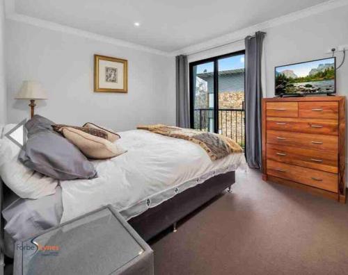 a bedroom with a bed and a dresser and a window at Snowcreek 2 Alpine Chalet, Private Garage in Thredbo
