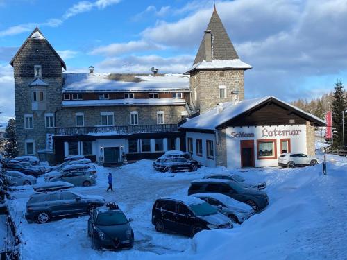 a large building with cars parked in the snow at Hotel Castel Latemar in Carezza al Lago