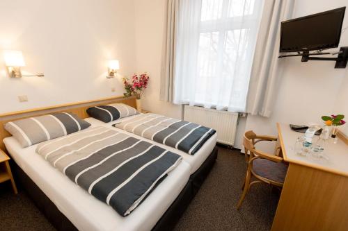 Habitación de hotel con 2 camas, escritorio y TV. en Hotel Albena - garni Hotel, en Fürstenwalde
